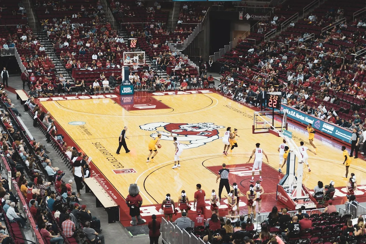 Spectators watching a college basketball game from the stands of a large arena