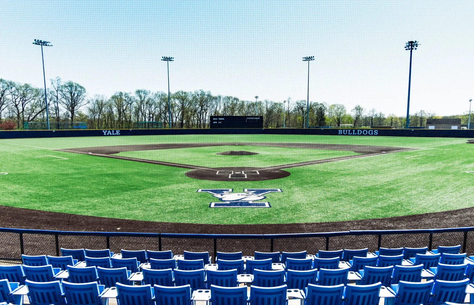Empty Yale Bulldogs baseball diamond seen from behind home plate with blue stadium seats in the foreground