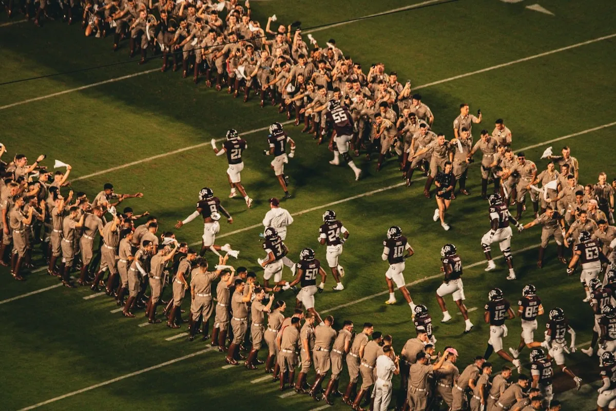 College football team running onto the field through a tunnel of cheering fans