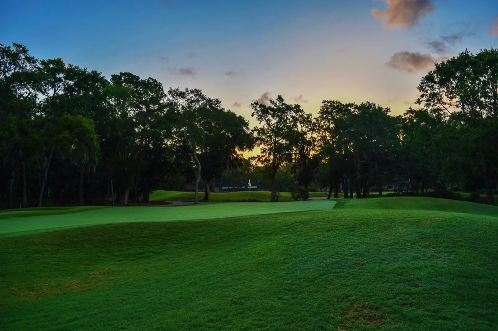 A golf course fairway at sunset with trees lining both sides