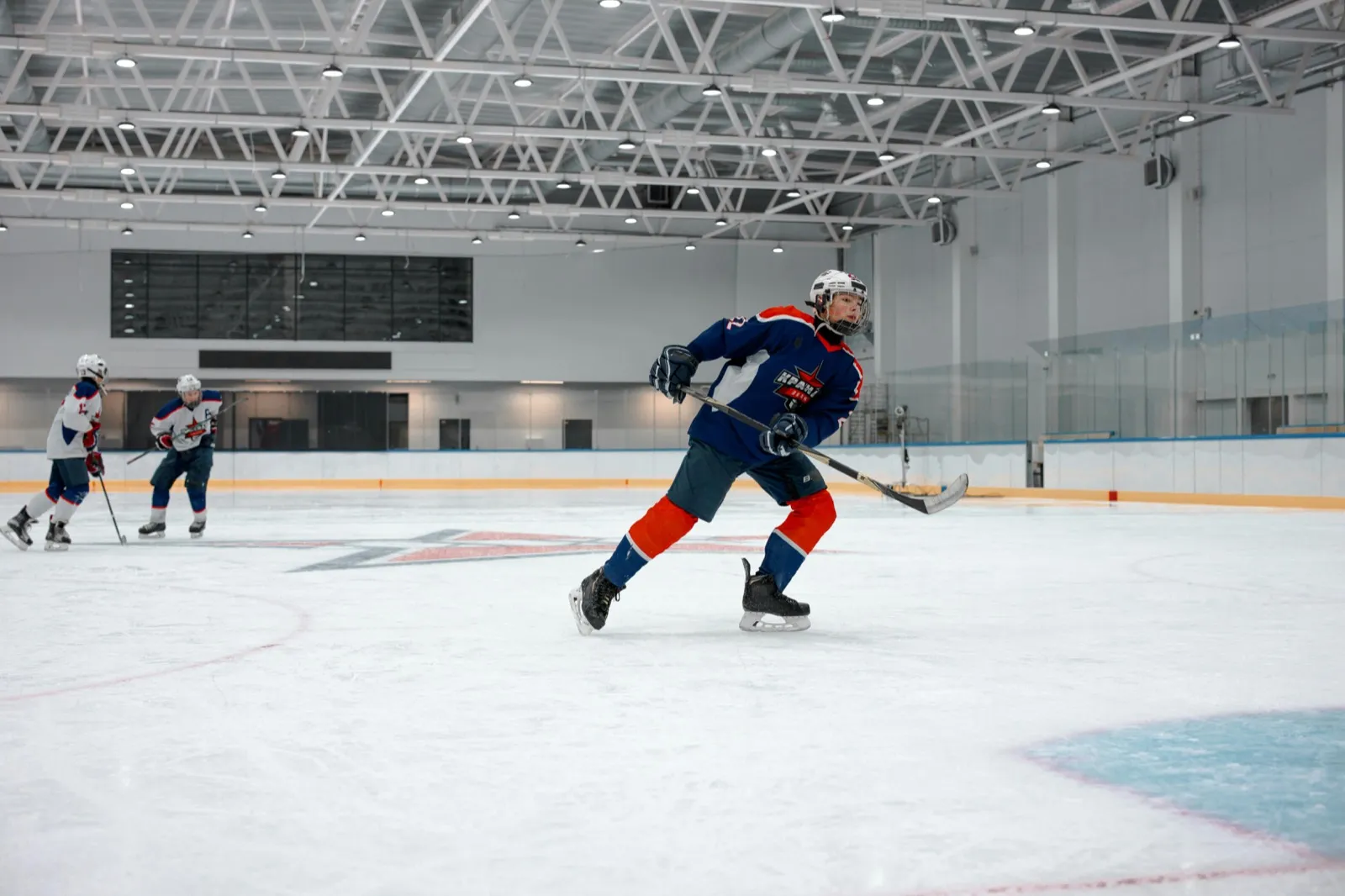 A hockey player in a blue jersey skating with the puck on an indoor rink