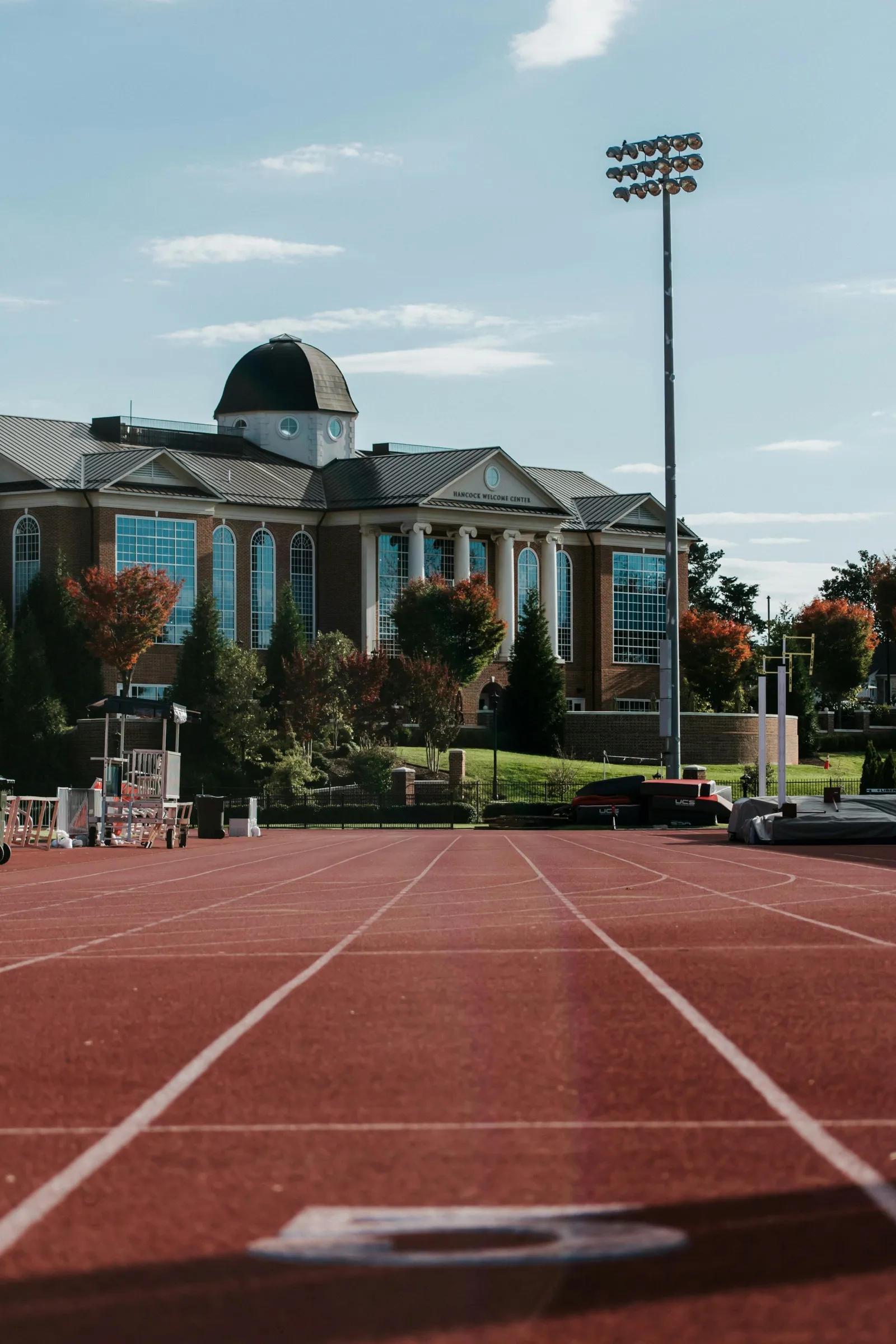 A college running track seen from the starting blocks with a brick campus building visible in the background