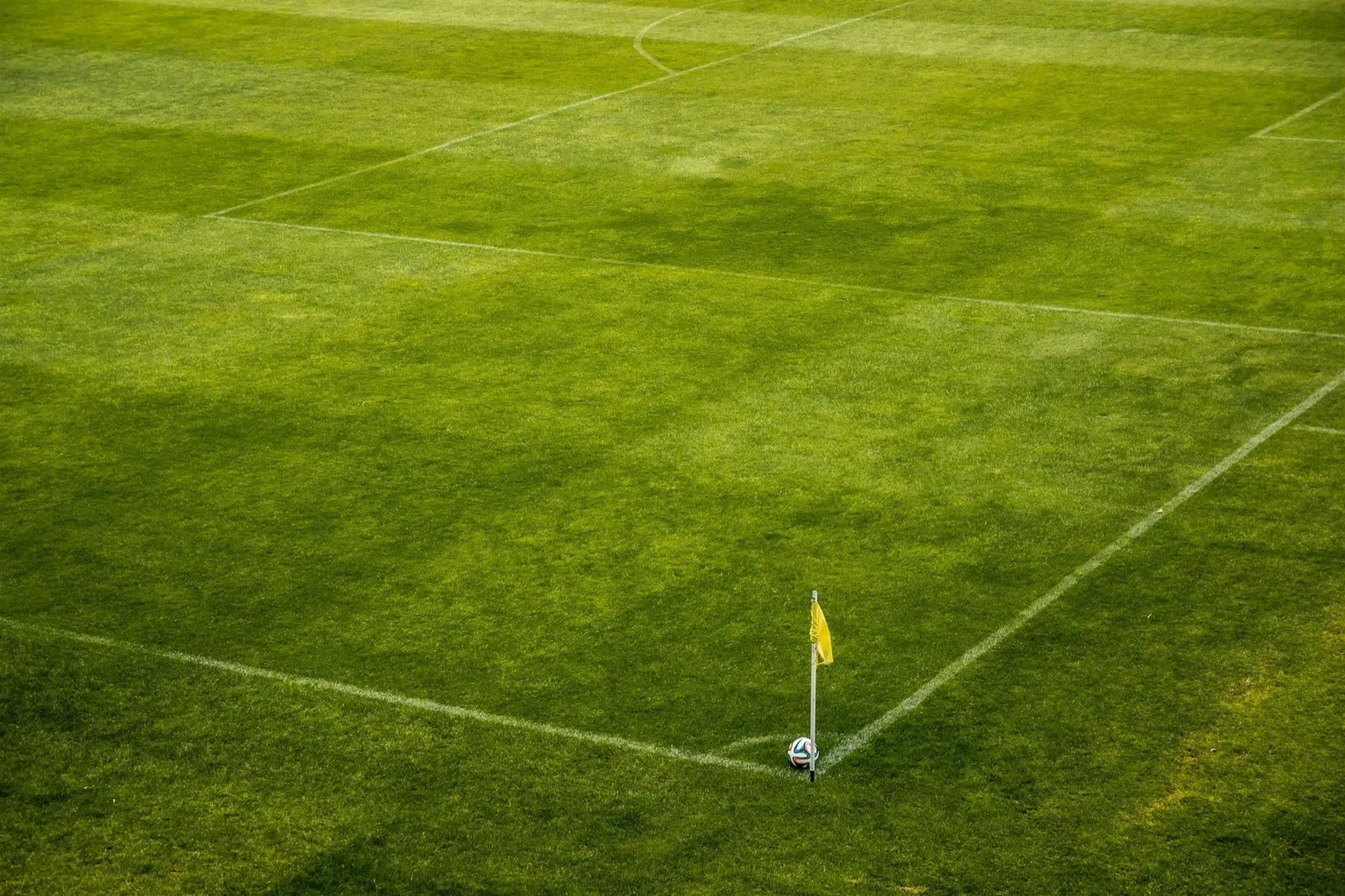 Soccer field corner flag and ball on green grass before a match