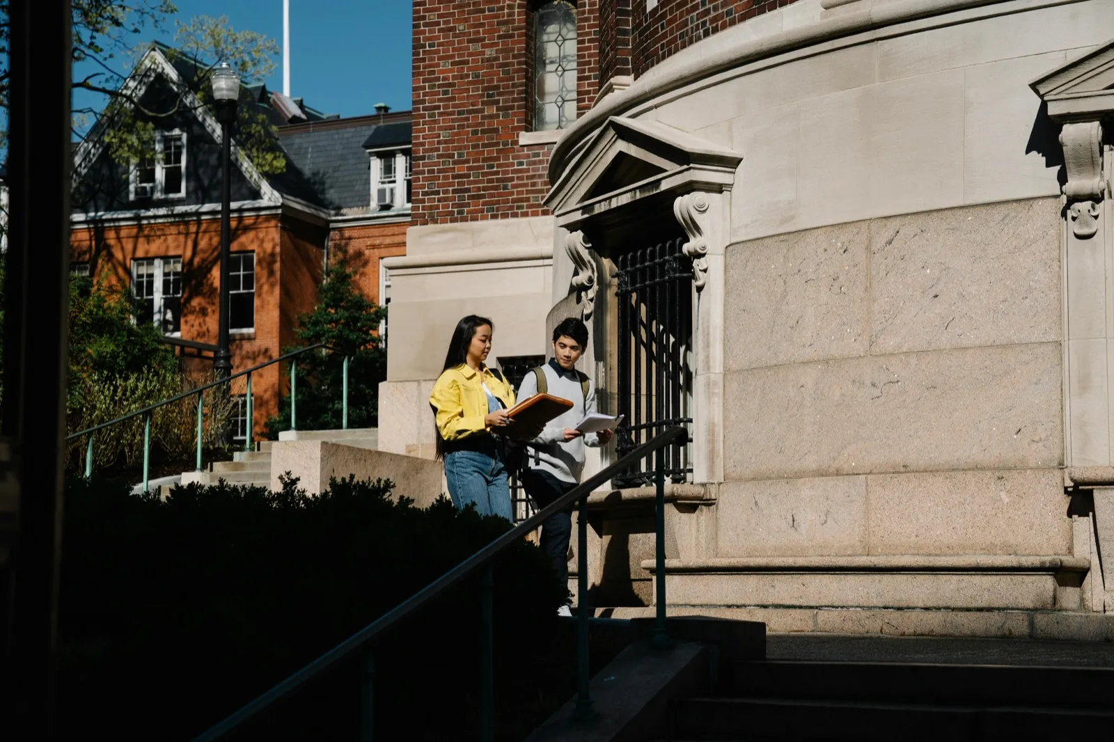Two students reading together on the steps of a campus building
