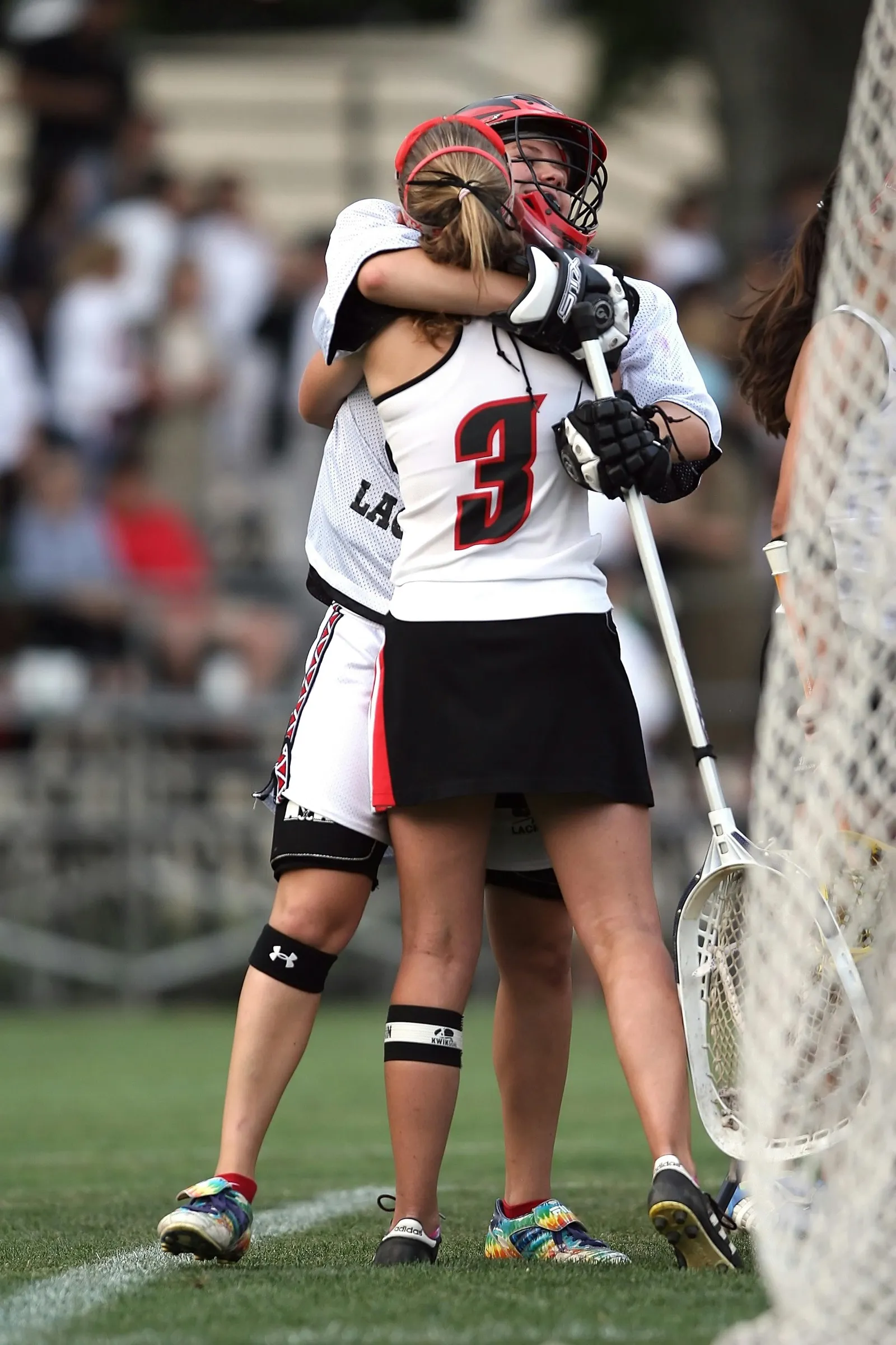 Women’s lacrosse players celebrating with their goalie after a play
